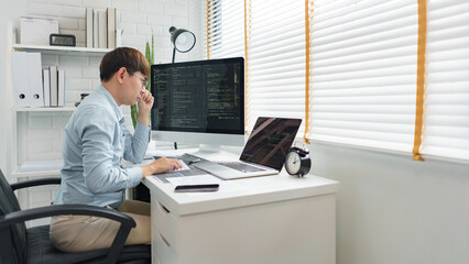 Wall Mural - software development concept, male programmer looking data on laptop and typing codes on keyboard