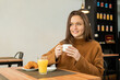 © ADDICTIVE STOCK - Happy young woman having breakfast in restaurant
