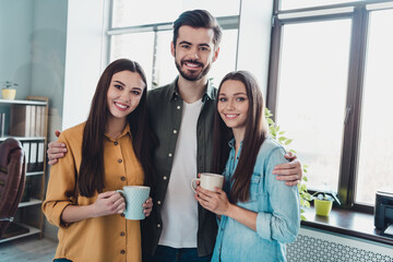 Wall Mural - Portrait of three business people embrace hold coffee cup project development wear casual indoors