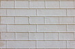 Texture of a plastered beige brick wall with exposed cement joints.