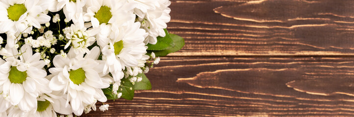 Wall Mural - Bouquet of white chamomile chrysanthemums on wooden background banner with copy space. Wide panoramic header. Gift flowers basket for the holiday