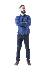 confident cool young bearded man standing and looking away with crossed hands. full body isolated on