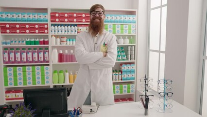 Wall Mural - Young redhead man pharmacist smiling confident standing with arms crossed gesture at pharmacy