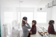 Son Watching Mother Brushing Hair In Morning Bathroom