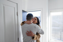 Affectionate Couple Hugging And Kissing At Front Door Of Home