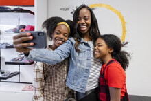 Happy Mother And Daughters With Smart Phone Taking Selfie Hair Salon