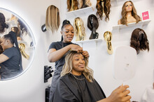 Hairstylist Adjusting Wig On Customer With Mirror In Beauty Salon