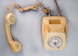 © kinomaster - Old yellow antique rotary telephone with removed receiver on blue background. Vintage landline home phone with dial, twisted cable and reciever handset. Conversation apparatus. Top view.
