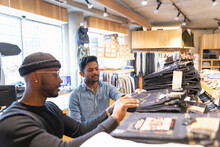 Clothing Store Worker Helping Customer Shopping For Jeans