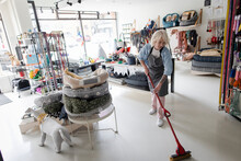 Female Business Owner With Mop Mopping Pet Store Floor