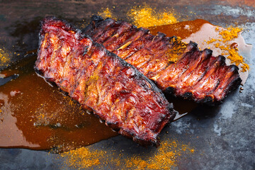 Wall Mural - Barbecue pork spare loin ribs St Louis cut with hot honey chili sauce served as close-up on a rustic black board
