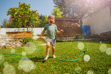 Laughing Handsome Boy Run Around Water Sprinkler In The Garden