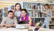 © JackF - Group of people looking at laptop screen together in library and preparing for exam