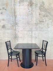 Black wood table and chair set isolated on concrete wall with copy space.