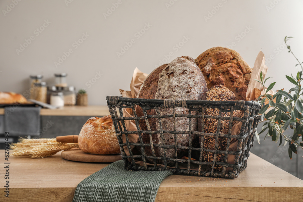 Basket with loaves of fresh bread on table in kitchen