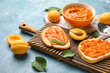 Wall Mural - Wooden board of tasty sandwiches with apricot jam on color background, closeup