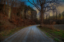 Down A Gravel Road At Dusk By A Large Bluff 