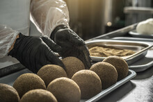 Farmer In Black Gloves Sprinkle Black Pepper On A Cheese Ball. The Production Process Of Belper Knolle Cheese