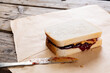 Peanut butter and jelly sandwich on brown paper with table knife at table