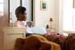 © Wavebreak Media - Thoughtful african american woman sitting on sofa with coffee mug looking away in living room