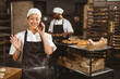 © Wavebreak Media - Smiling asian mid adult female baker talking on smart phone while standing in bakery