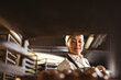 © Wavebreak Media - Smiling asian mid adult female baker keeping braided bread tray in rack