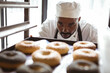 © Wavebreak Media - Close-up of african american mid adult male baker looking at donuts in baking tray on rack