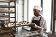© Wavebreak Media - African american mid adult male baker removing baked bread tray from rack in bakery