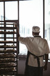 © Wavebreak Media - Rear view of african american mid adult male baker standing by rack by window in bakery