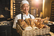© Wavebreak Media - Portrait of happy asian mid adult female baker with fresh breads in basket while standing in bakery