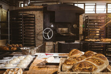 Loaf Of Bread And Dough On Tables With Oven In Background At Bakery