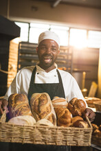 Portrait Of Happy African American Mid Adult Male Baker Holding Basket With Fresh Breads In Bakery