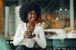 Leinwandbild Motiv Young afro woman taking break and drinking coffee in cafe