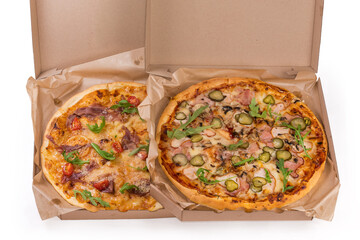 Two different pizza with various ham in open cardboard boxes