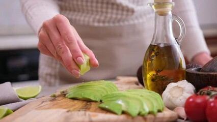 Wall Mural - woman squeezing fresh lime juice on a sliced fresh avocado fruit