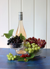 Canvas Print - Still life with wine and grapes. Colorful photo of bottle of rose wine and different sorts of grapes. Seasonal fruit on a table. 