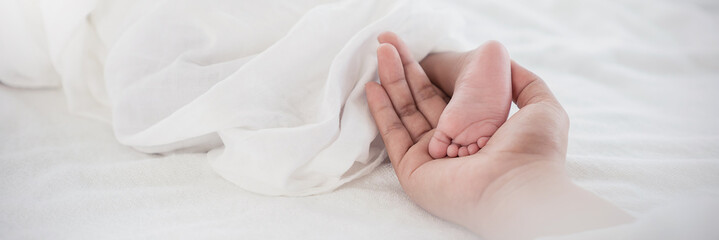 close up mother’s hands holding black african newborn baby feet. closeup feet of newborn baby. healt