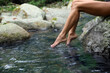 Woman dipping feet in mountain river outdoors, closeup. Space for text