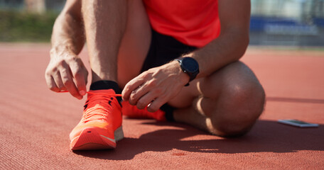  Sport man athlete tying laces for jogging on treadmillat the stadium.