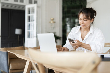 A female freelancer works in an office online doing a design project on a website. The programmer uses a laptop