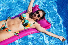 Relaxed woman sunbathing on inflatable ring in pool