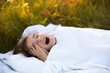 Girl sleeps on bed in grass, Sweet stretches and yawns sleepily, good morning in fresh air. Eco-friendly, healthy sleep, Protection from mosquitoes, clean nature, ecology, children's health