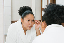 Ethnic Woman Plucking Eyebrows In Bathroom