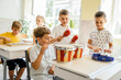 © Iryna - Group of five excited children boys and girls playing musical instruments at class.
