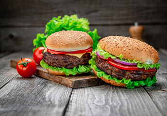 Wall Mural - Two delicious homemade burgers of beef on an old wooden table. Fat unhealthy food close-up.