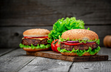 Wall Mural - Two delicious homemade burgers of beef on an old wooden table. Fat unhealthy food close-up.