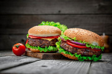 Wall Mural - Two delicious homemade burgers of beef on an old wooden table. Fat unhealthy food close-up.