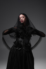 Wall Mural - young asian model in gothic outfit with black veil posing isolated on grey.