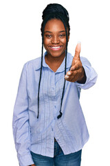 Canvas Print - Young african american woman wearing casual clothes smiling friendly offering handshake as greeting and welcoming. successful business.