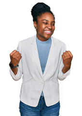 Wall Mural - Young african american woman wearing business clothes very happy and excited doing winner gesture with arms raised, smiling and screaming for success. celebration concept.